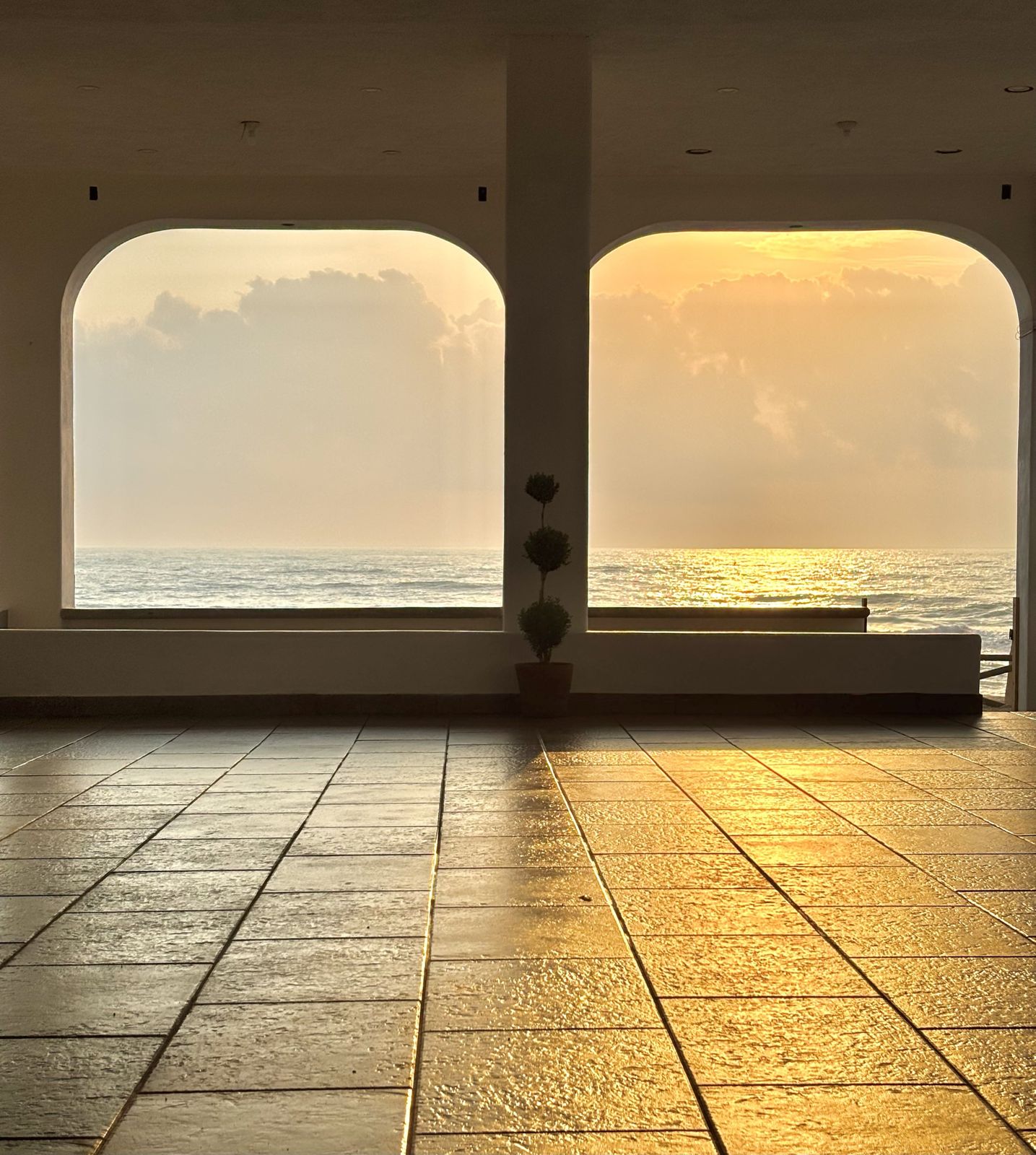 Atardecer sobre el mar visto entre los arcos del salón