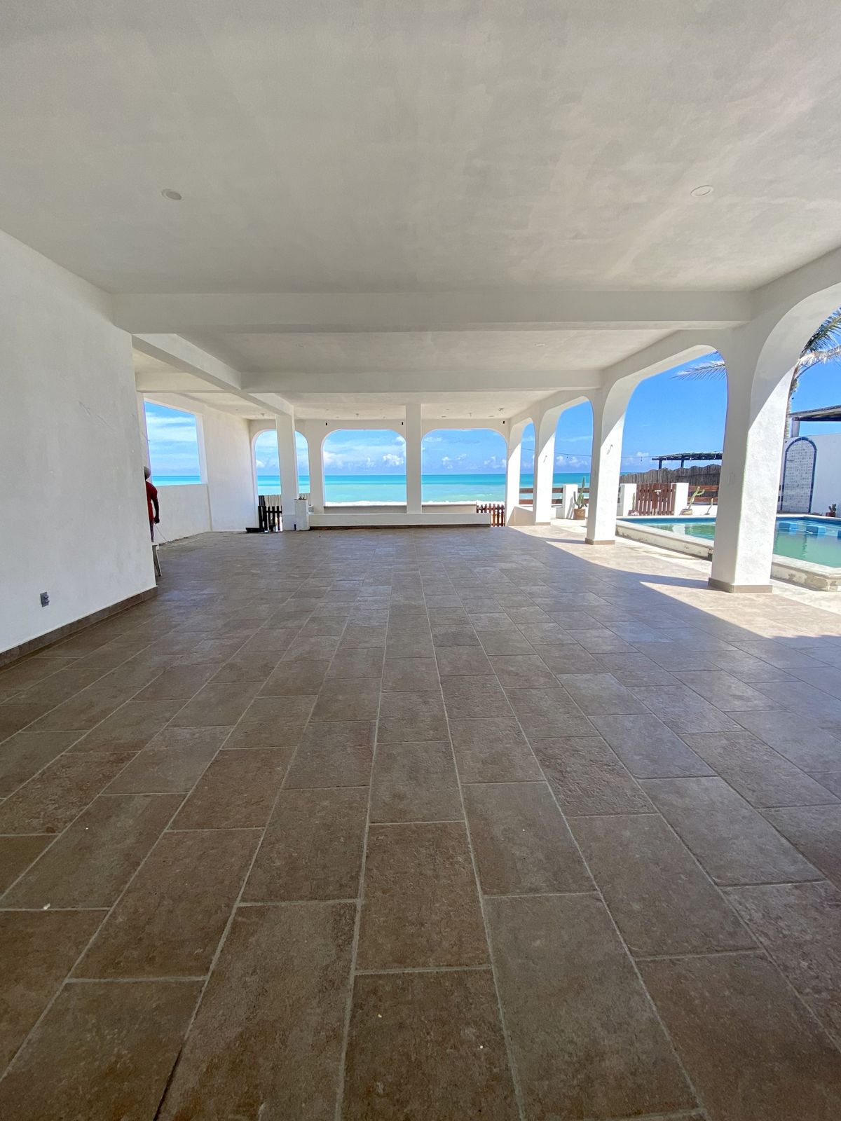 Salón techado con arcos abiertos hacia el mar